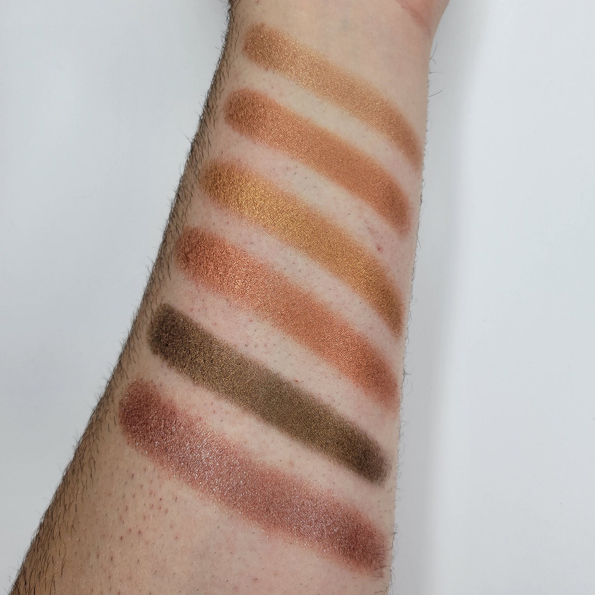 Side view of Cinnamon Roll Bronze Shimmer Eyeshadow pan showing warm bronze tones and reflective shimmer particles