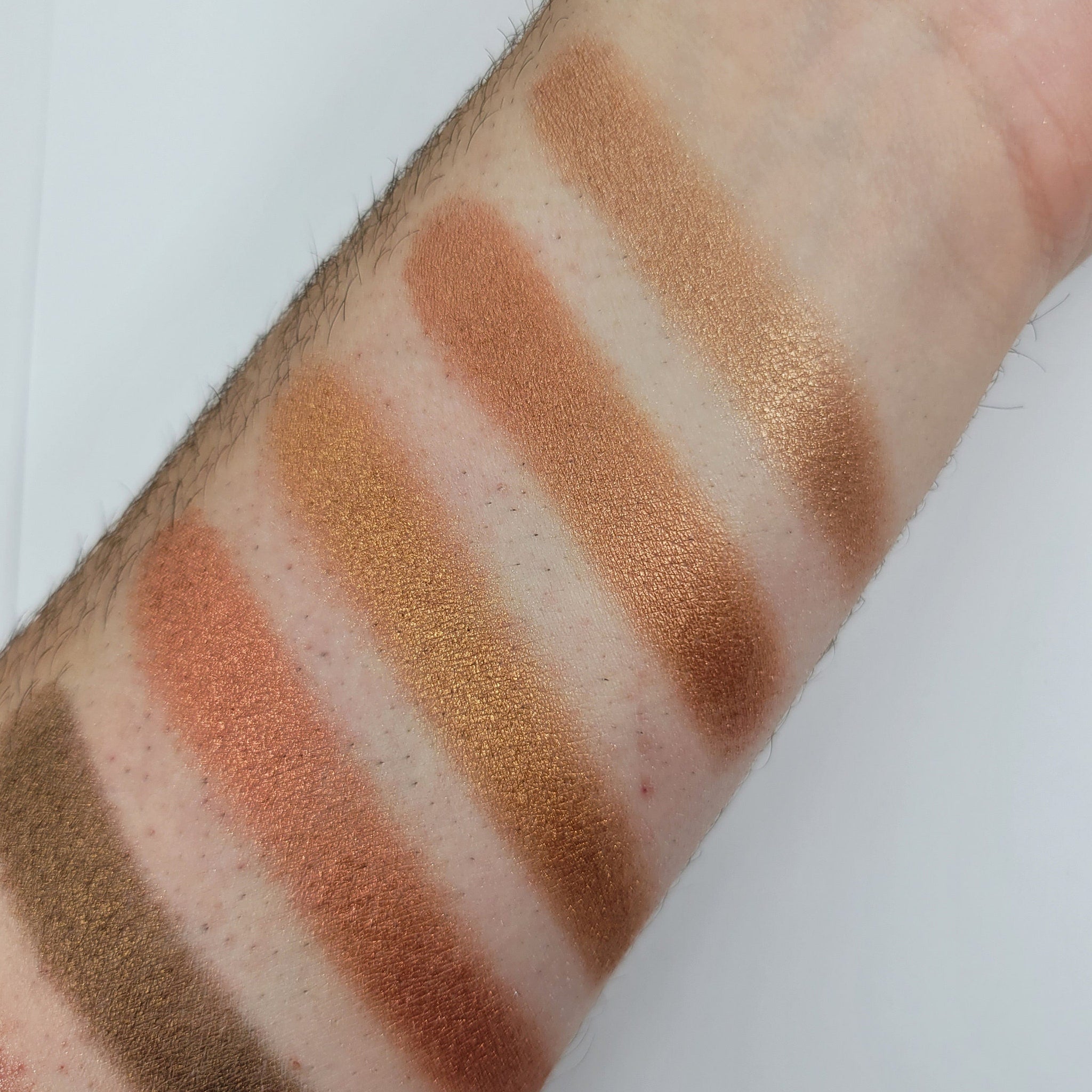 Hand applying bronze shimmer eyeshadow with fingertip to eyelid, showcasing warm cinnamon tones