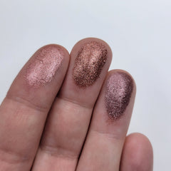Close-up of fingertips applying shimmery pink eyeshadow to eyelid with soft blending brush