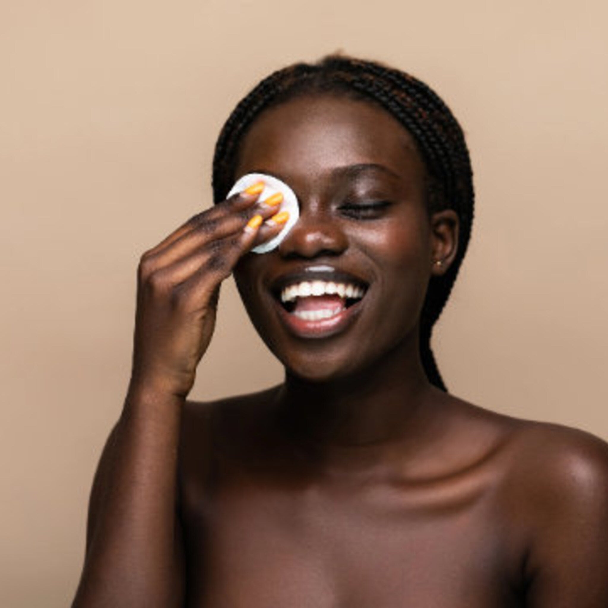 Cotton pad wiping eye, round white pad, dark skin tone, woman smiling with closed eye