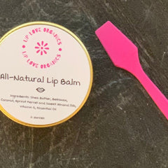 Lip balm tin with gold rim and pink applicator, "Lip Love Organics" text visible on label, on dark surface