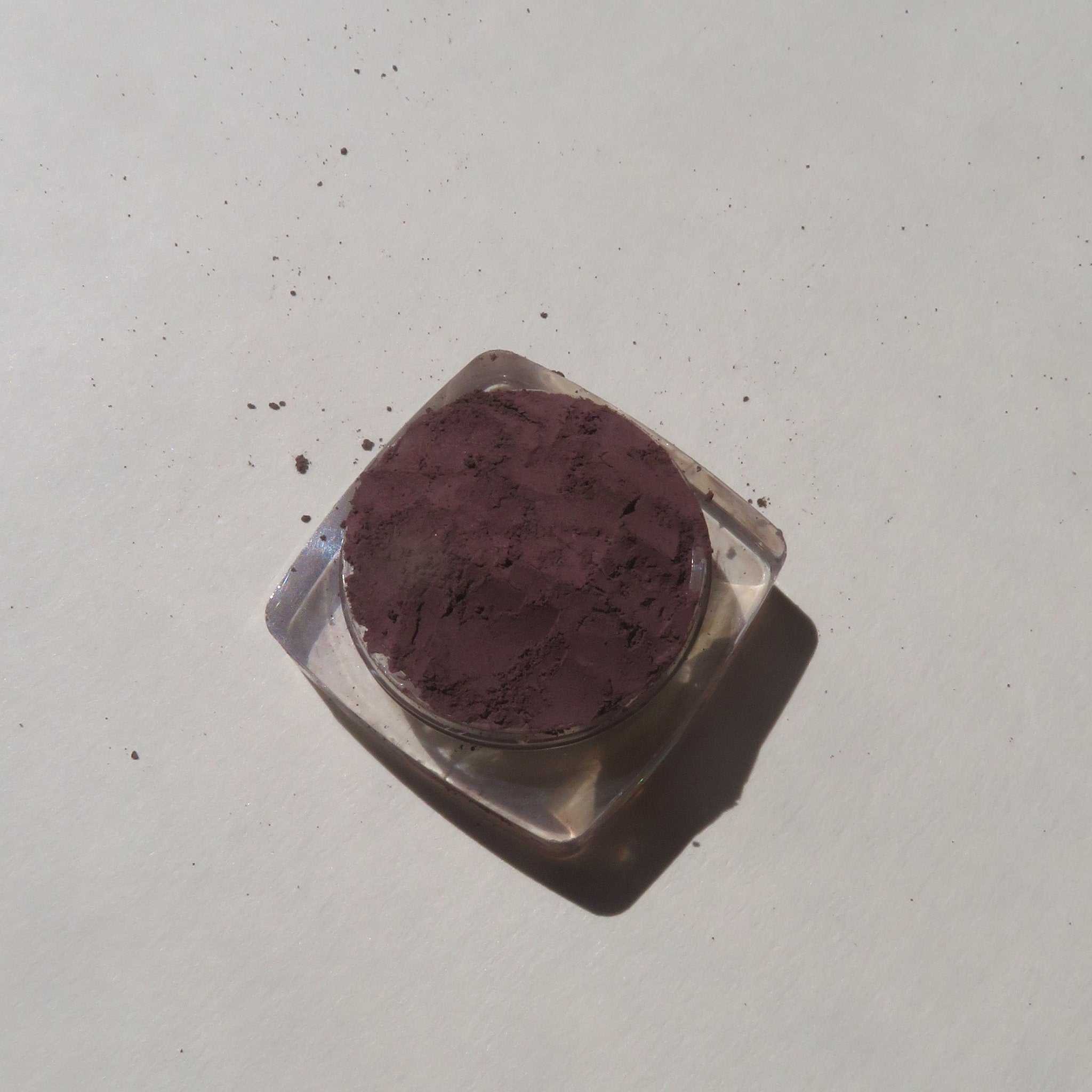 Close-up of super dark muted purple loose mineral eyeshadow with matte finish in open jar