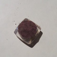 Close-up of super dark muted purple loose mineral eyeshadow with matte finish in open jar