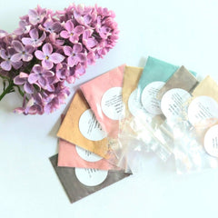 Nine small round pots of vegan mineral eyeshadow in earthy tones, arranged in a grid on a neutral background.