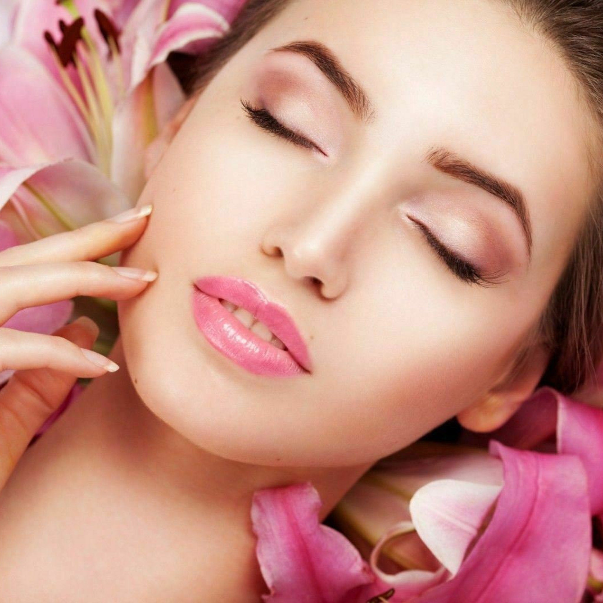 Woman with closed eyes, pink lipstick, and pink flower petals around face