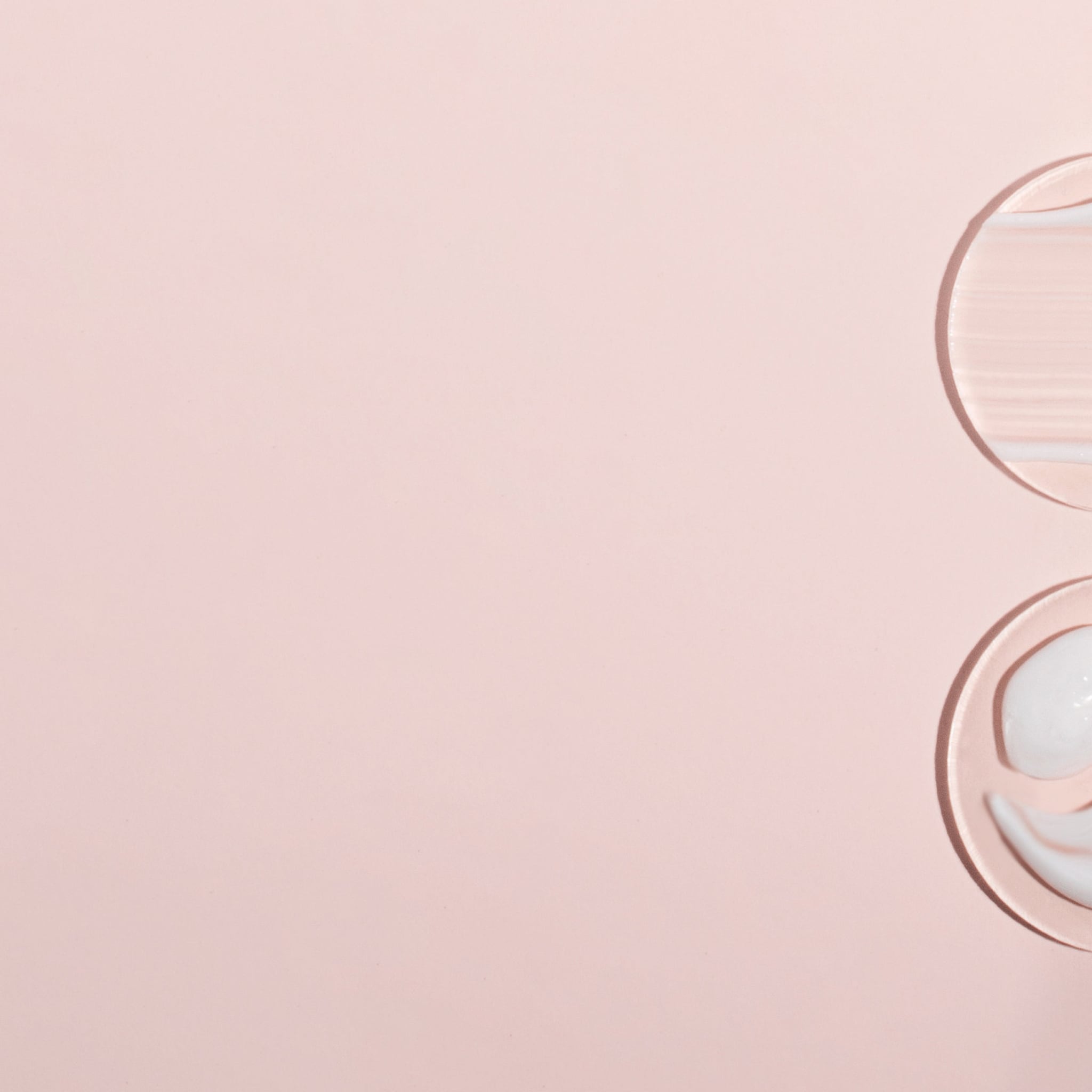 Skincare samples on pink background, with white and translucent textures, and circular shapes