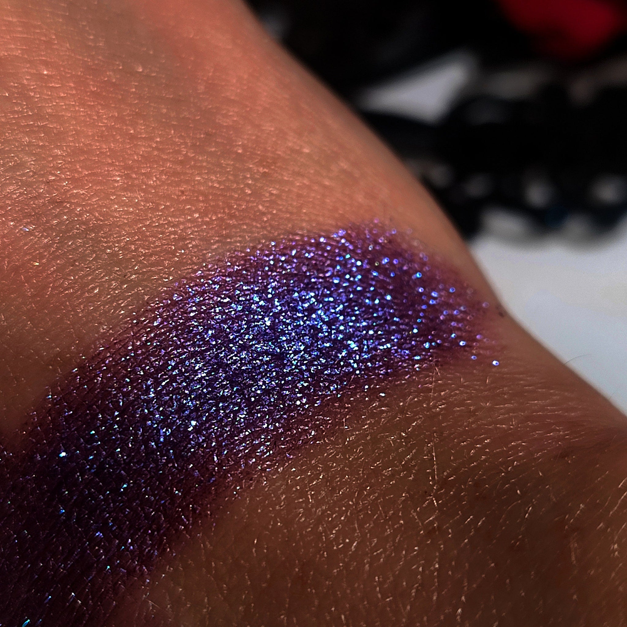 Glitter eyeshadow swatch, purple and blue iridescent shimmer, applied on skin