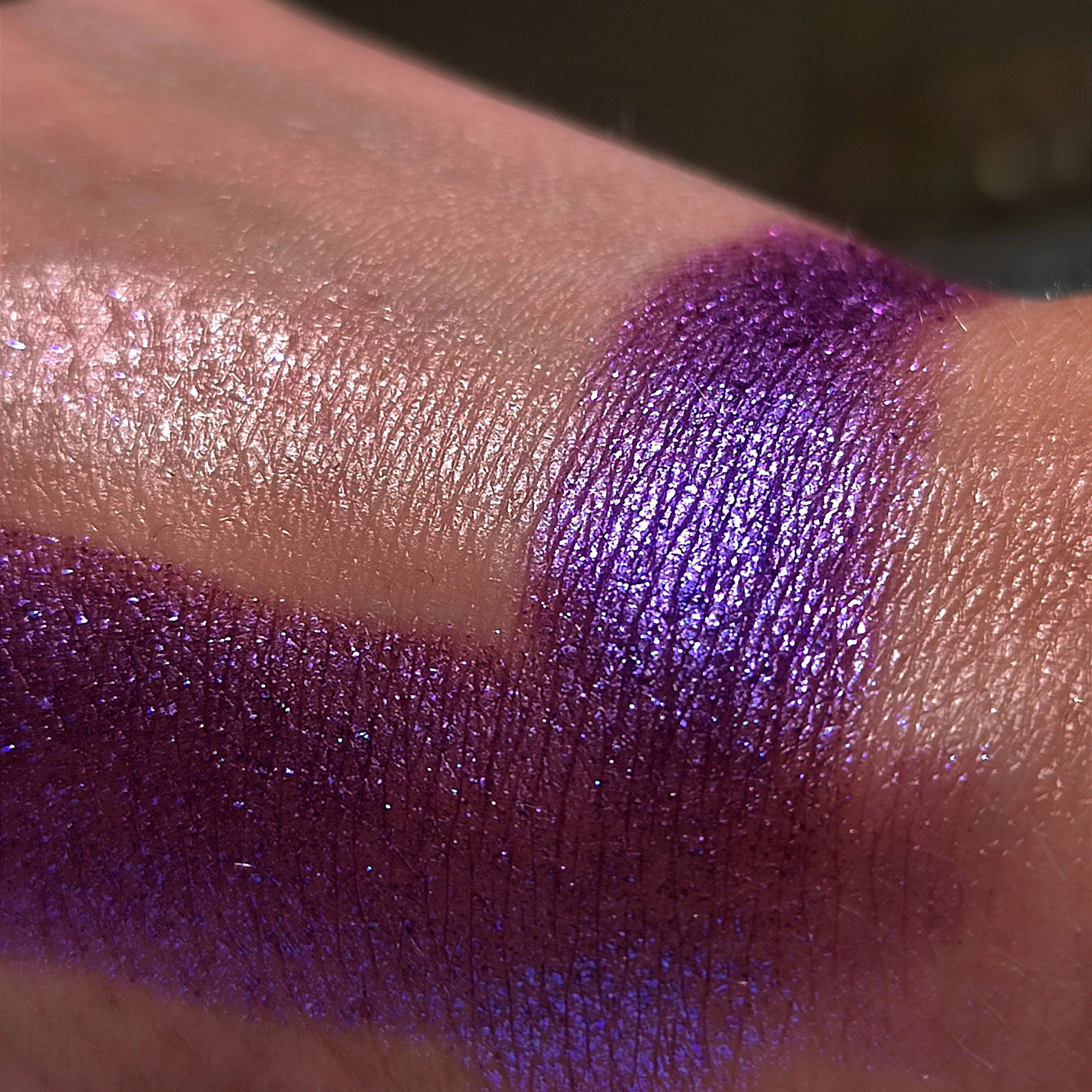 Purple eyeshadow swatch with shimmer, metallic finish, applied on skin