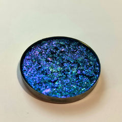 Blue and purple glitter eyeshadow with metallic container, close-up view