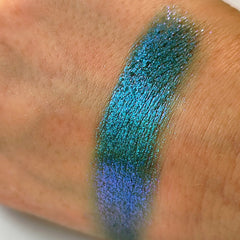 Eyeshadow swatch with teal and blue shimmer on skin, showing color and texture