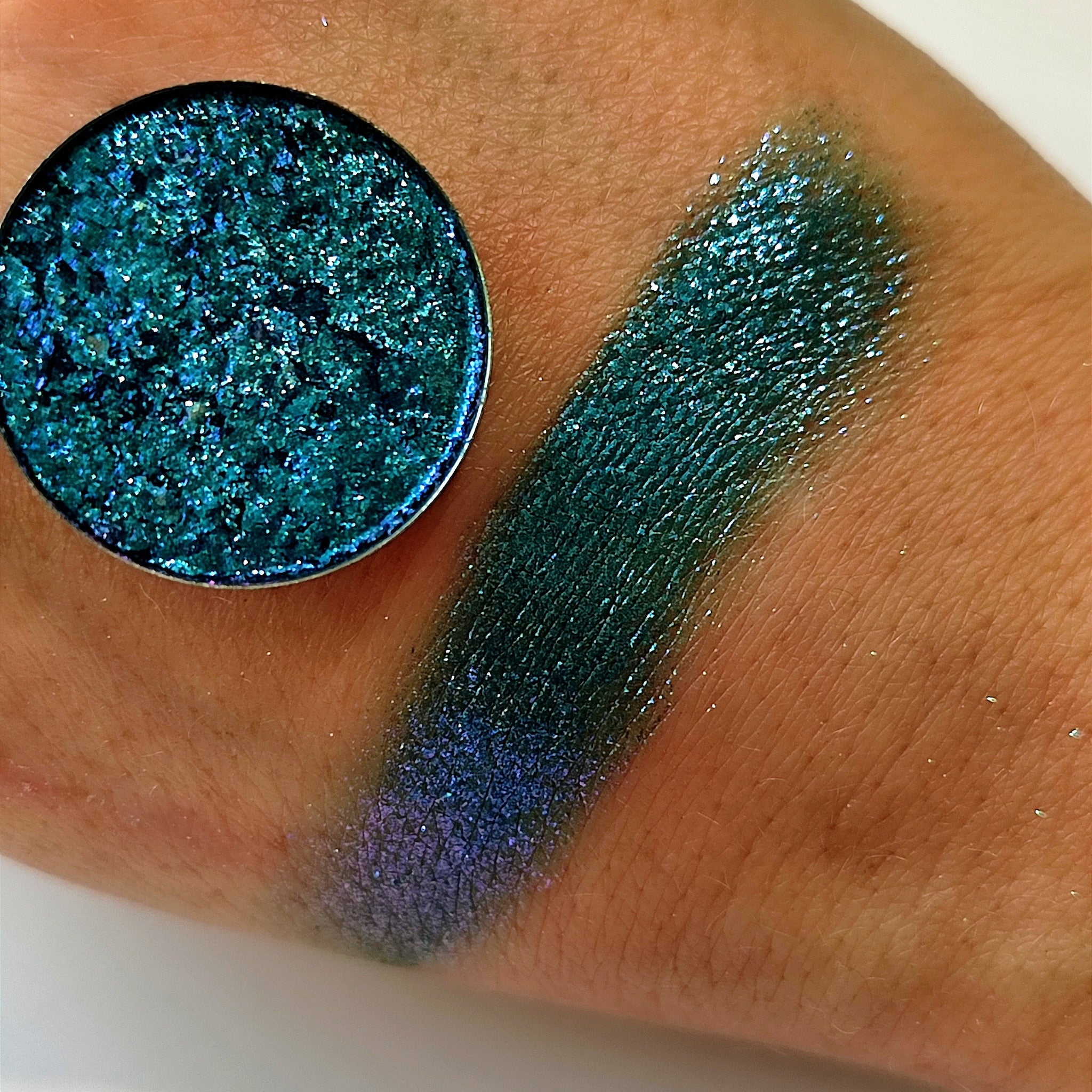 Eyeshadow swatch with teal and blue shimmer, applied on skin for color test