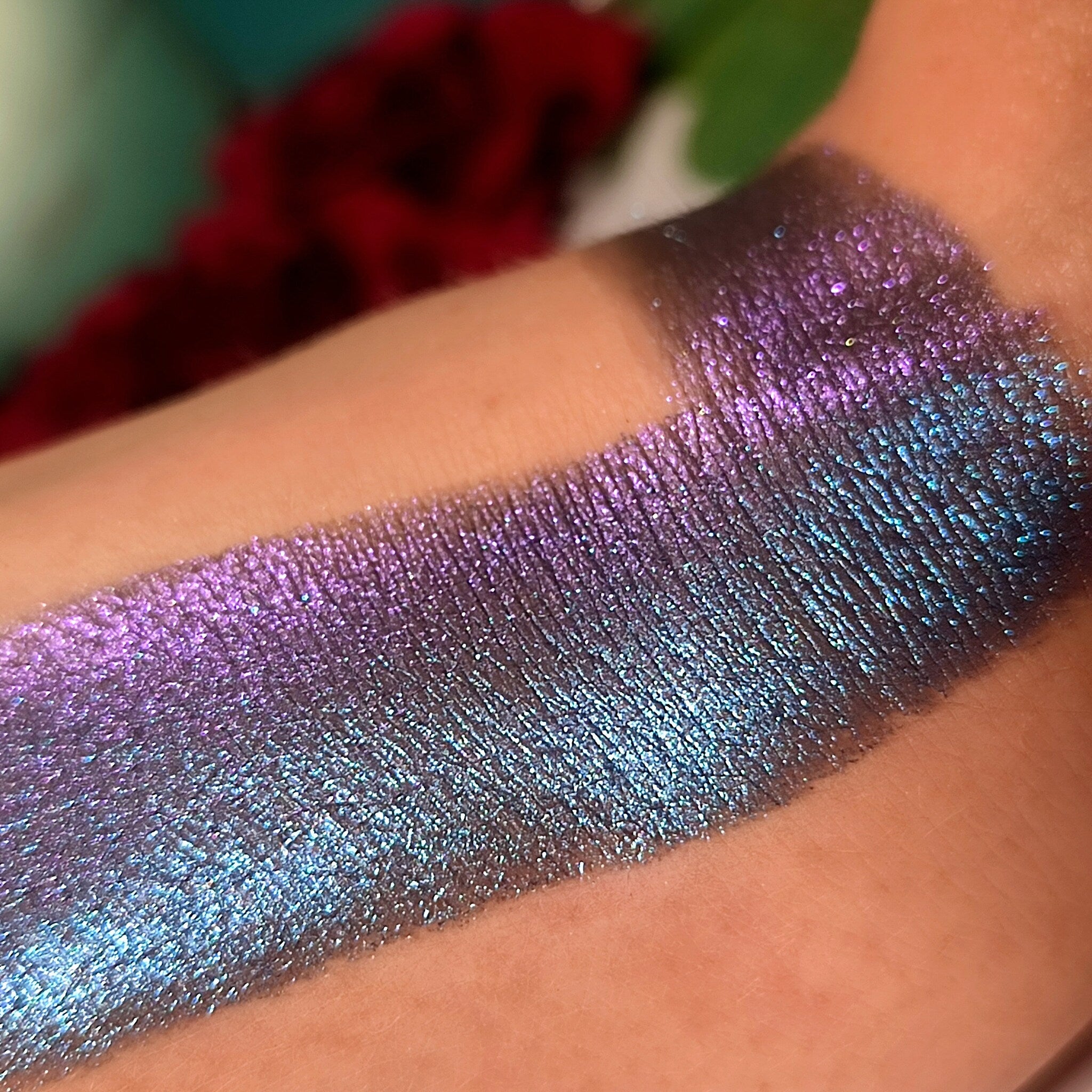 Eyeshadow swatch with iridescent purple, blue, and silver shimmer on skin