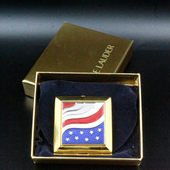 Compact mirror with gold frame, red, white, and blue flag design, and E Lauder branding in box