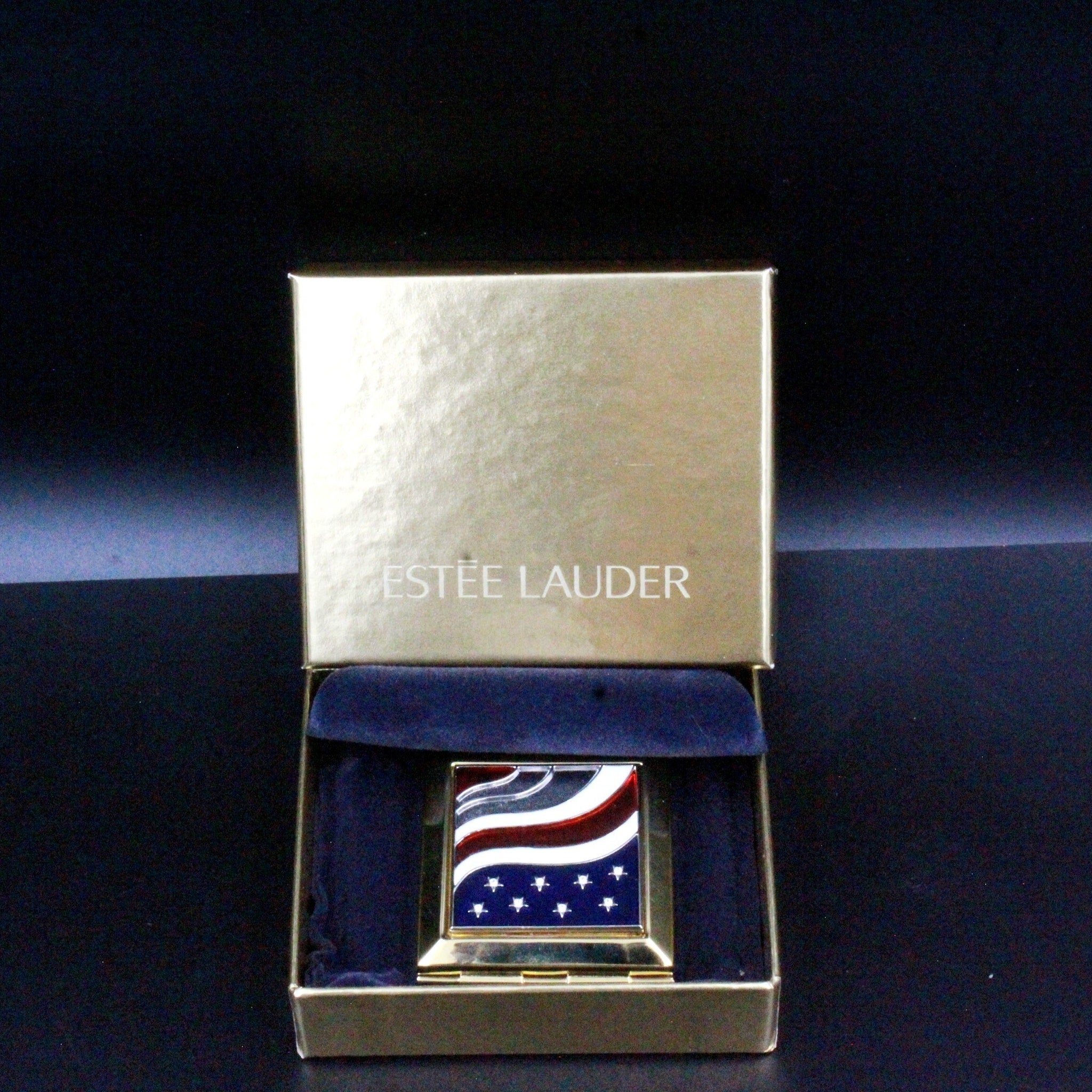 Estee Lauder compact with American flag design, gold metal case, and blue velvet lining