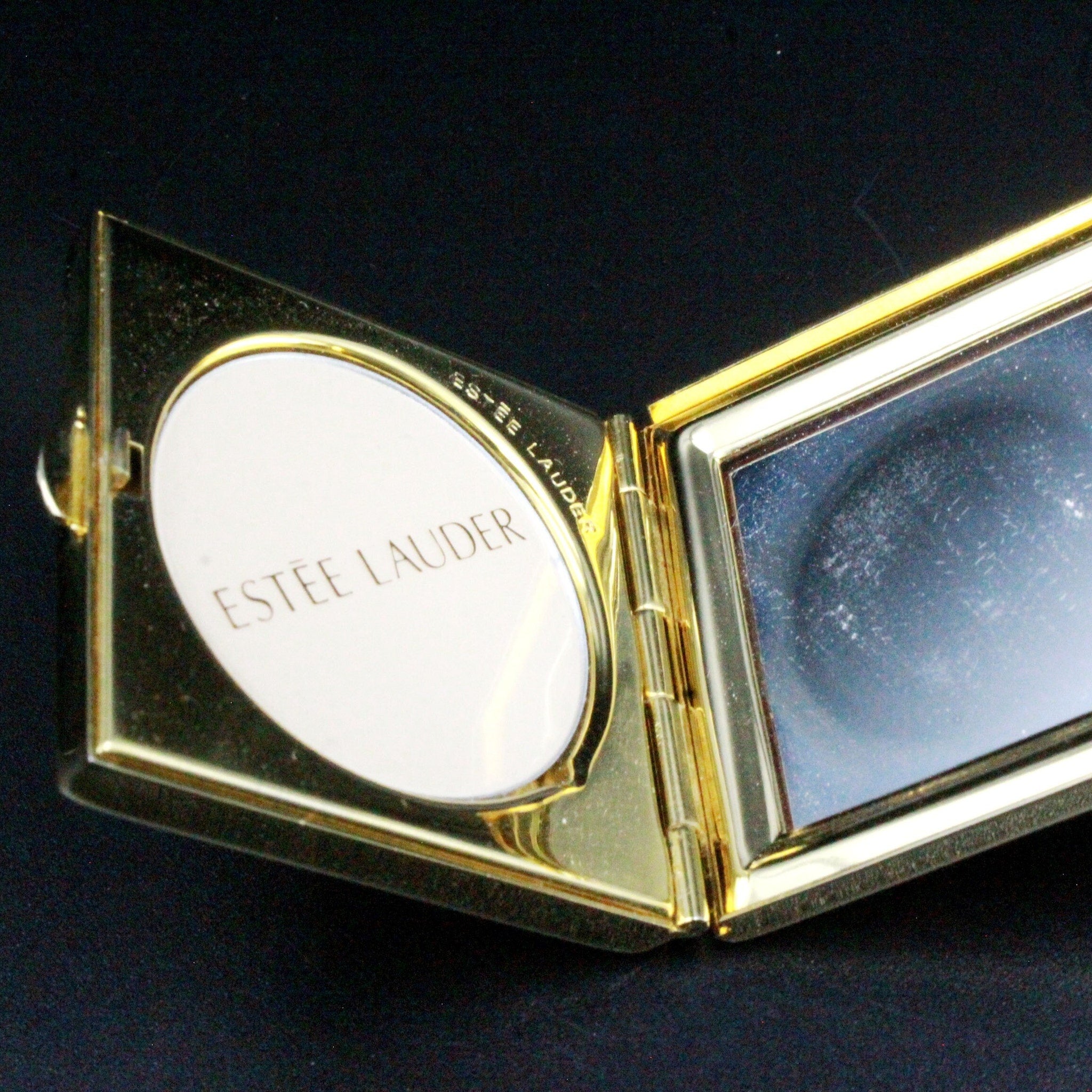 Estee Lauder compact with gold metal frame, white powder, and mirror inside