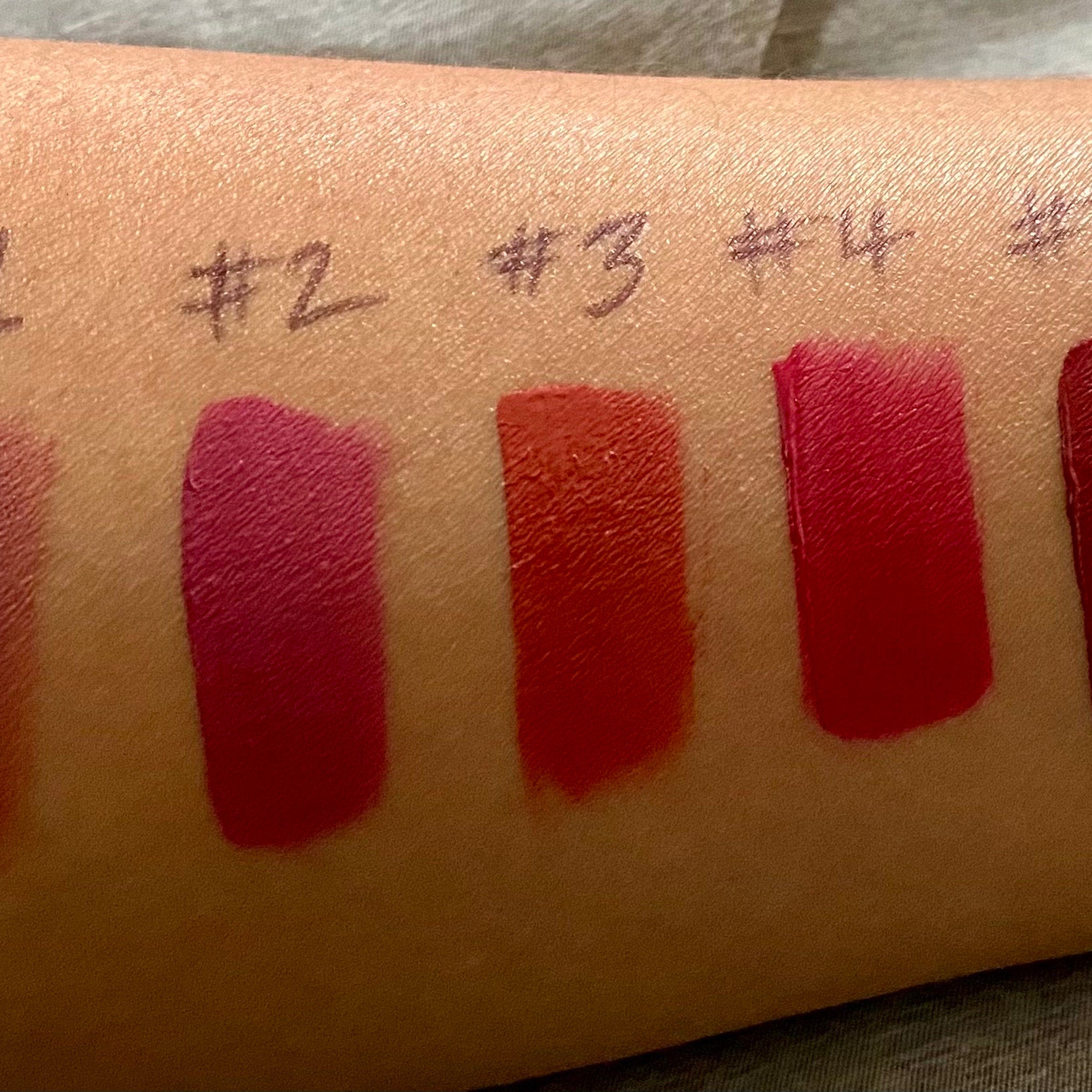 Lipstick swatches on skin in red, pink, and orange shades, numbered for comparison