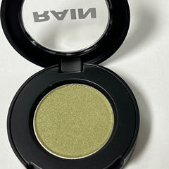 Close-up of shimmering golden sage eyeshadow pan showing metallic finish and finely milled texture
