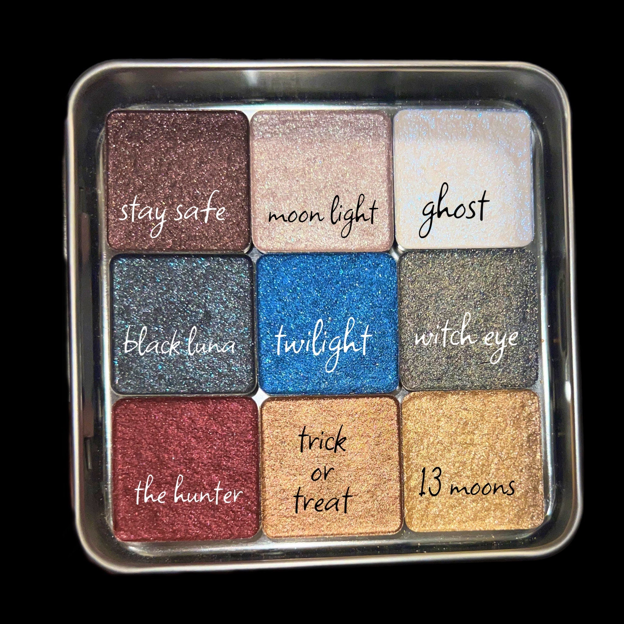 Hand applying shimmery blue eyeshadow from palette with brush, showcasing pigmented color payoff
