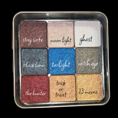 Hand applying shimmery blue eyeshadow from palette with brush, showcasing pigmented color payoff