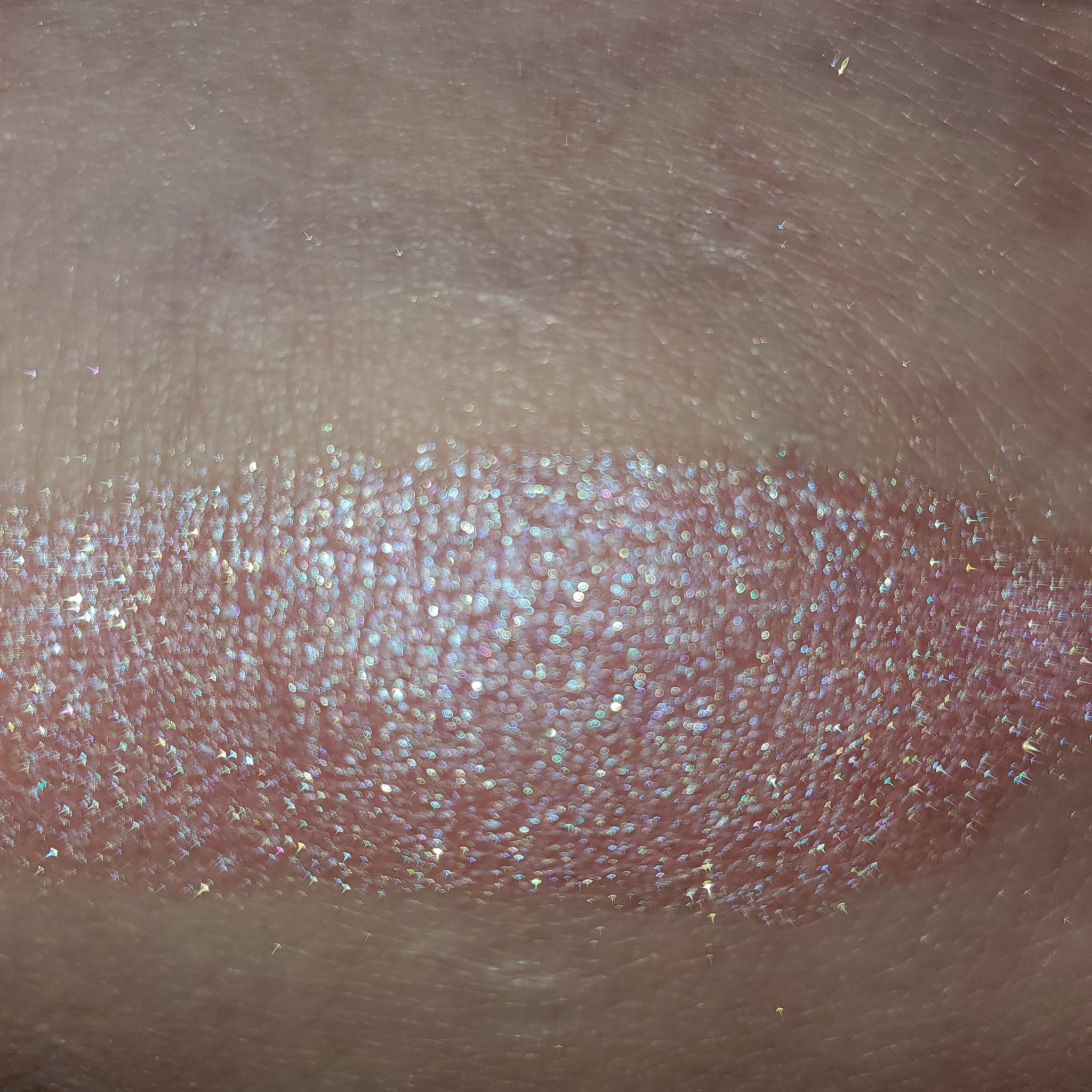 Close-up of fingertips applying shimmery bronze eye shadow to eyelid with blending brush