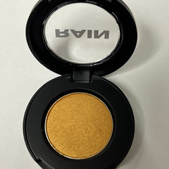 Close-up of sparkling gold eye shadow with shimmering metallic finish in compact case