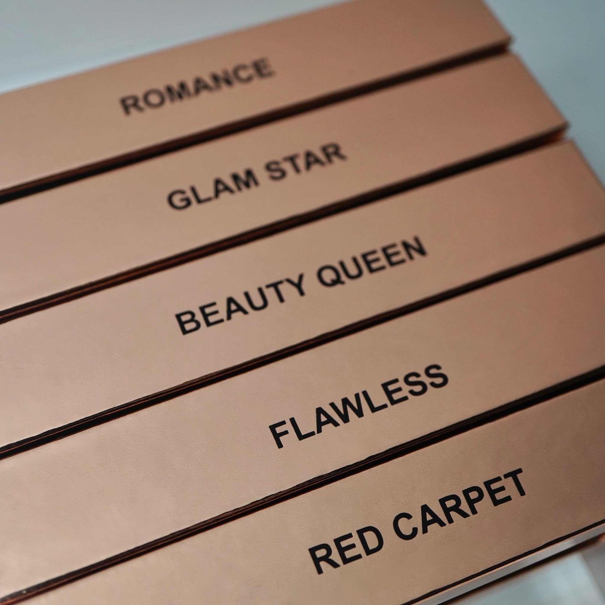 Boxes with rose gold color, black text, and dark trim, with product names visible