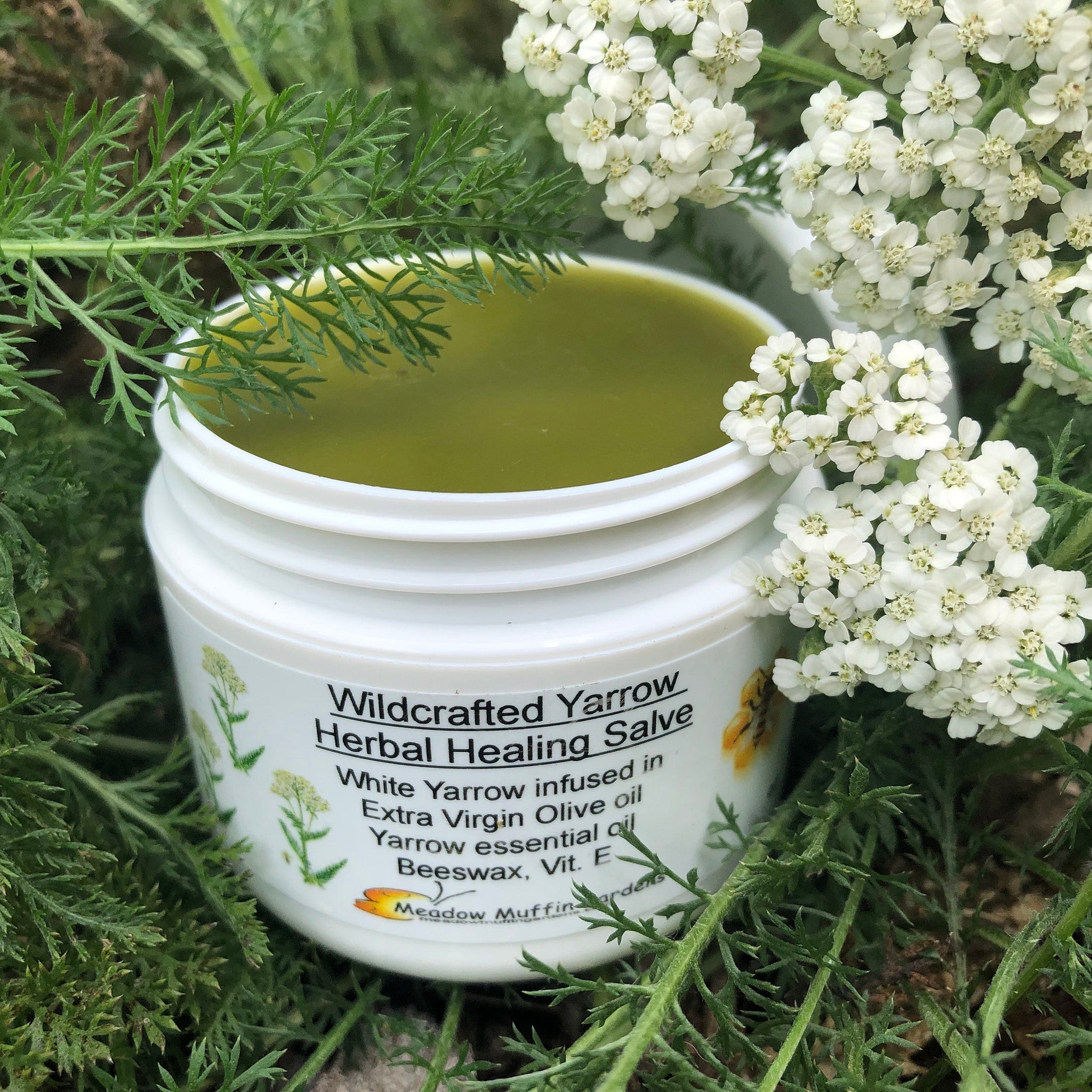 Amber glass jar of organic yarrow salve oil with gold lid and herbal label on wooden surface