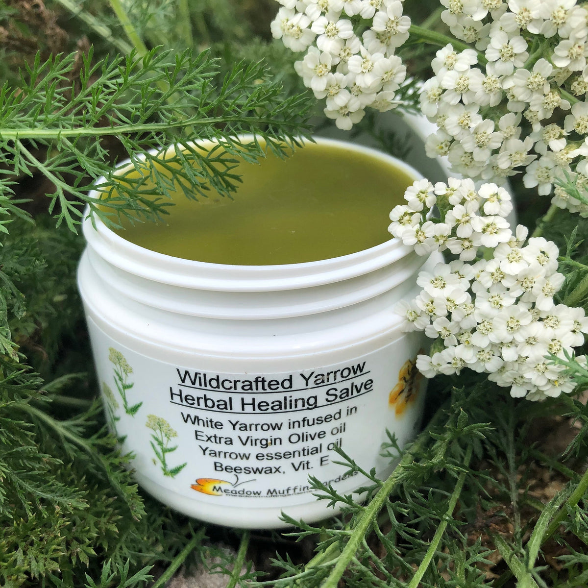 Amber glass jar of organic yarrow salve oil with gold lid and herbal label on wooden surface