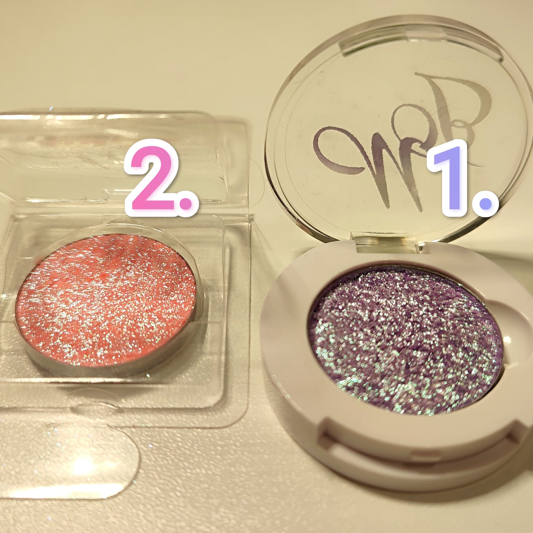 Eyeshadow compacts with pink and purple glitter, white and clear packaging, close-up view