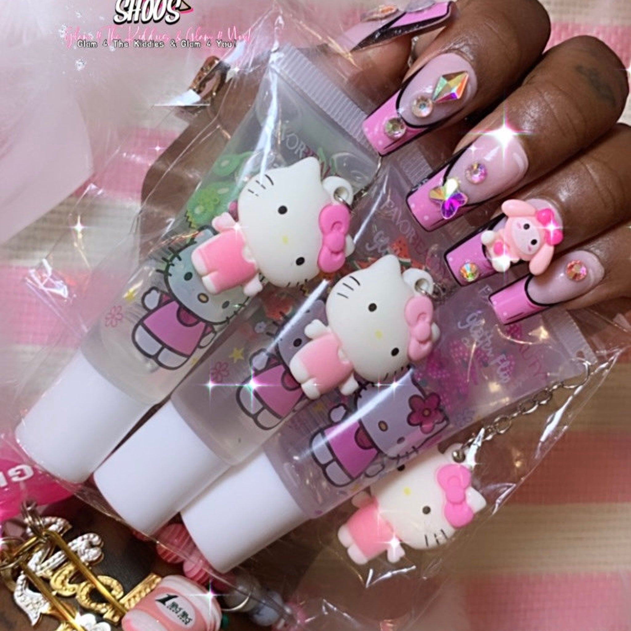 Lip gloss tubes with white, pink, and clear colors, Hello Kitty character charm, and white applicator tip