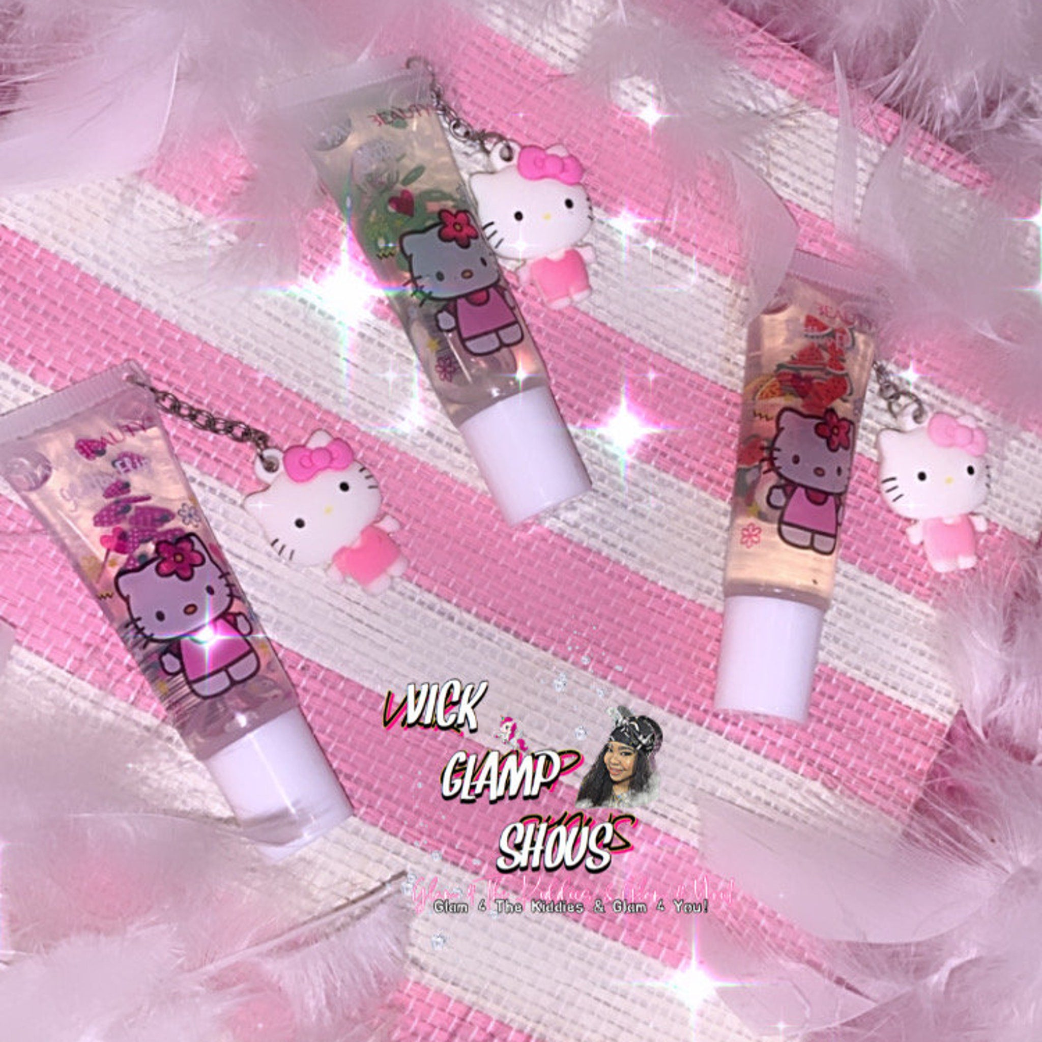 Lip gloss tubes with Hello Kitty charms, clear tubes, white caps, pink striped background