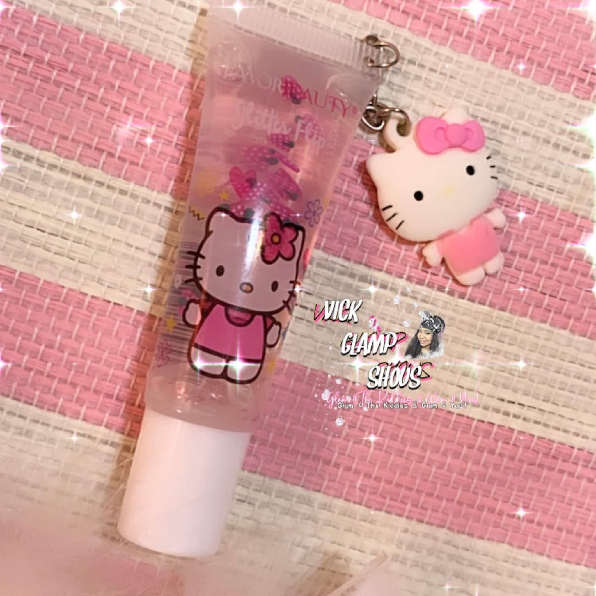 Lip gloss tube with Hello Kitty design, pink and clear, with a pink bow charm attached