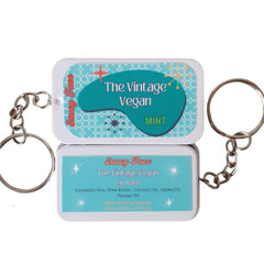 Lip balm tins with teal and white design, Saucy Face branding, attached to keychains.