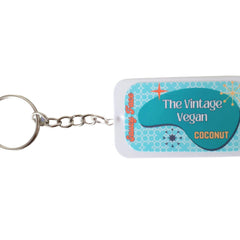 Lip balm with teal and white label, silver chain, and Saucy Face text