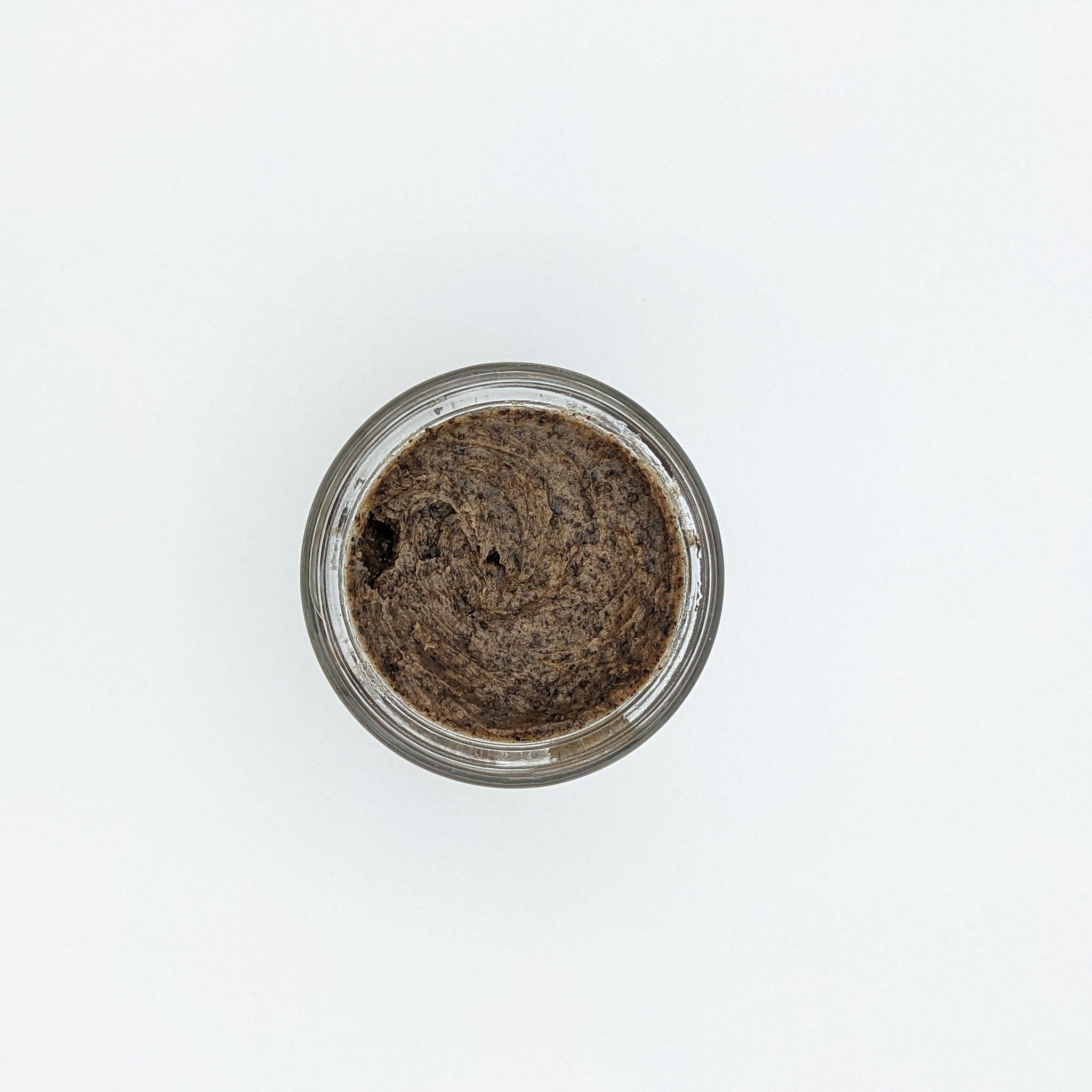 Brown scrub in glass jar, top-down view, on white background