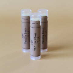 Lip balm tubes with brown paper labels, clear caps, and "Vanilla Bean" text visible