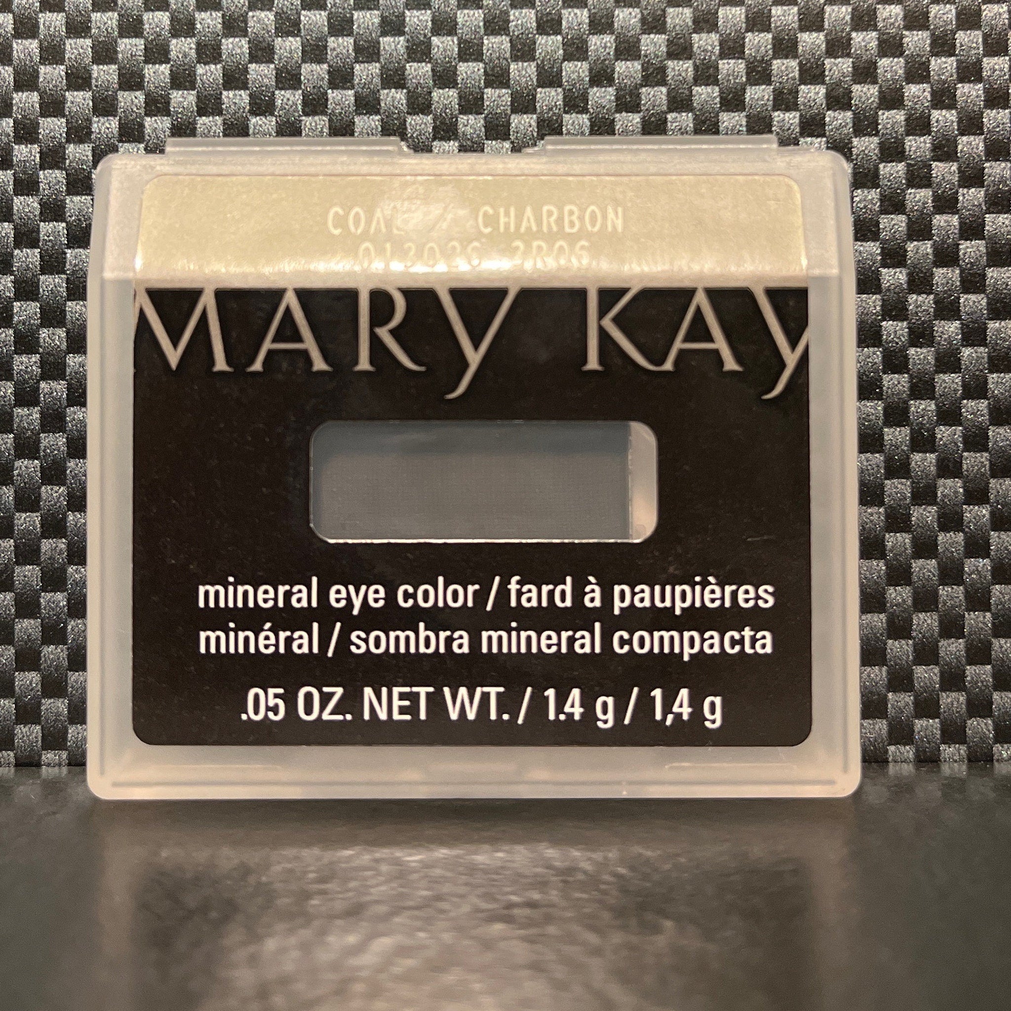Close-up of a makeup brush applying dark mineral coal eyeshadow to eyelid, creating a smoky effect