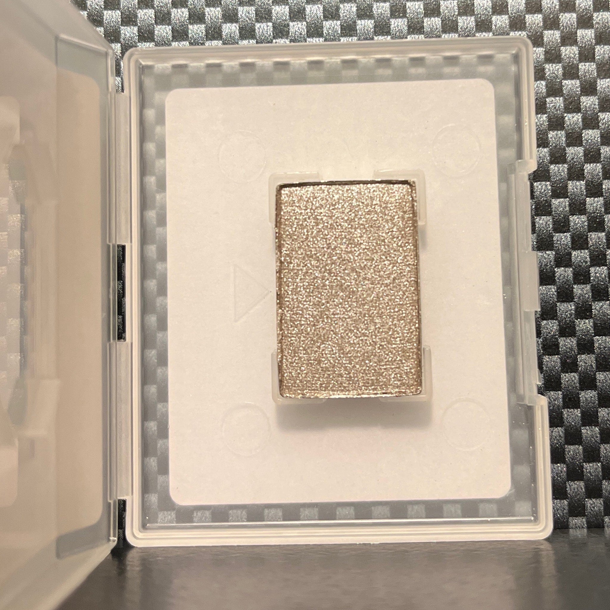 Hand applying shimmering polished stone mineral eye shadow to eyelid with fingertip for a metallic finish