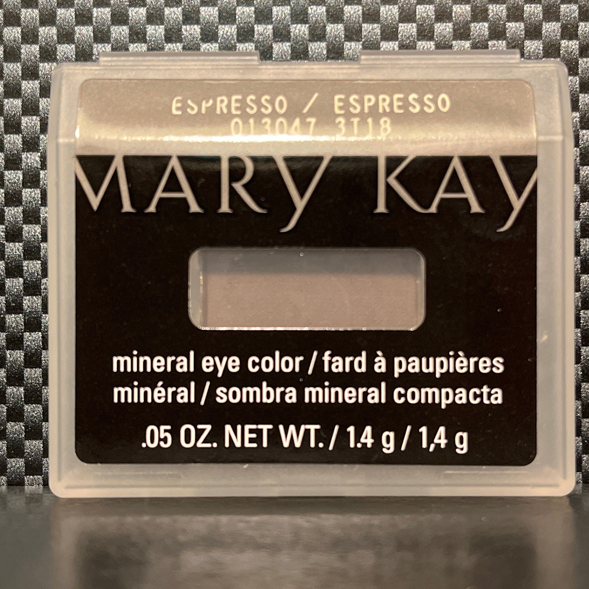 Side view of espresso brown mineral eye shadow in compact with reflective surface and subtle shimmer particles