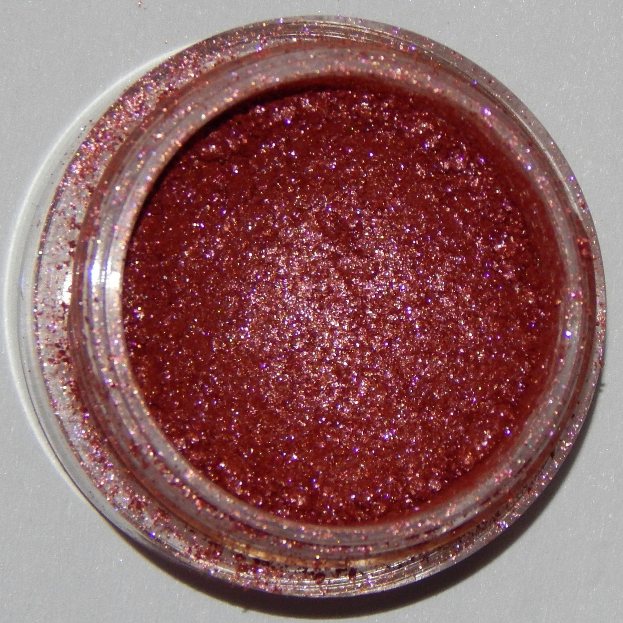 Close-up of Mineral Eyeshadow in Racy Lady showing vibrant pink shimmer powder in round compact case