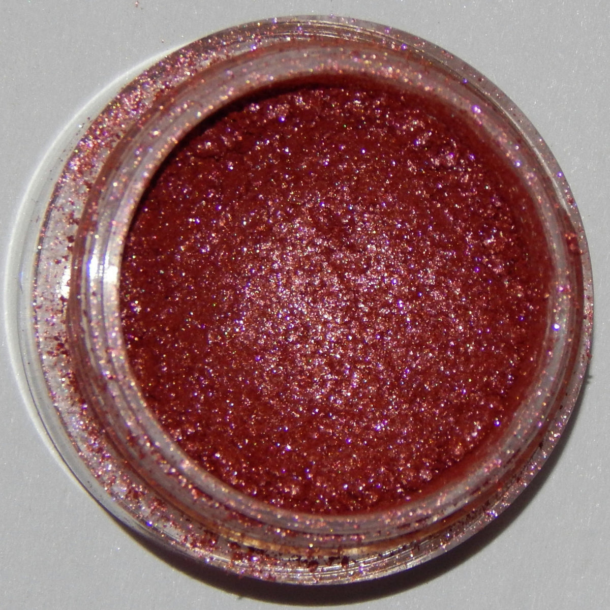 Close-up of Mineral Eyeshadow in Racy Lady showing vibrant pink shimmer powder in round compact case