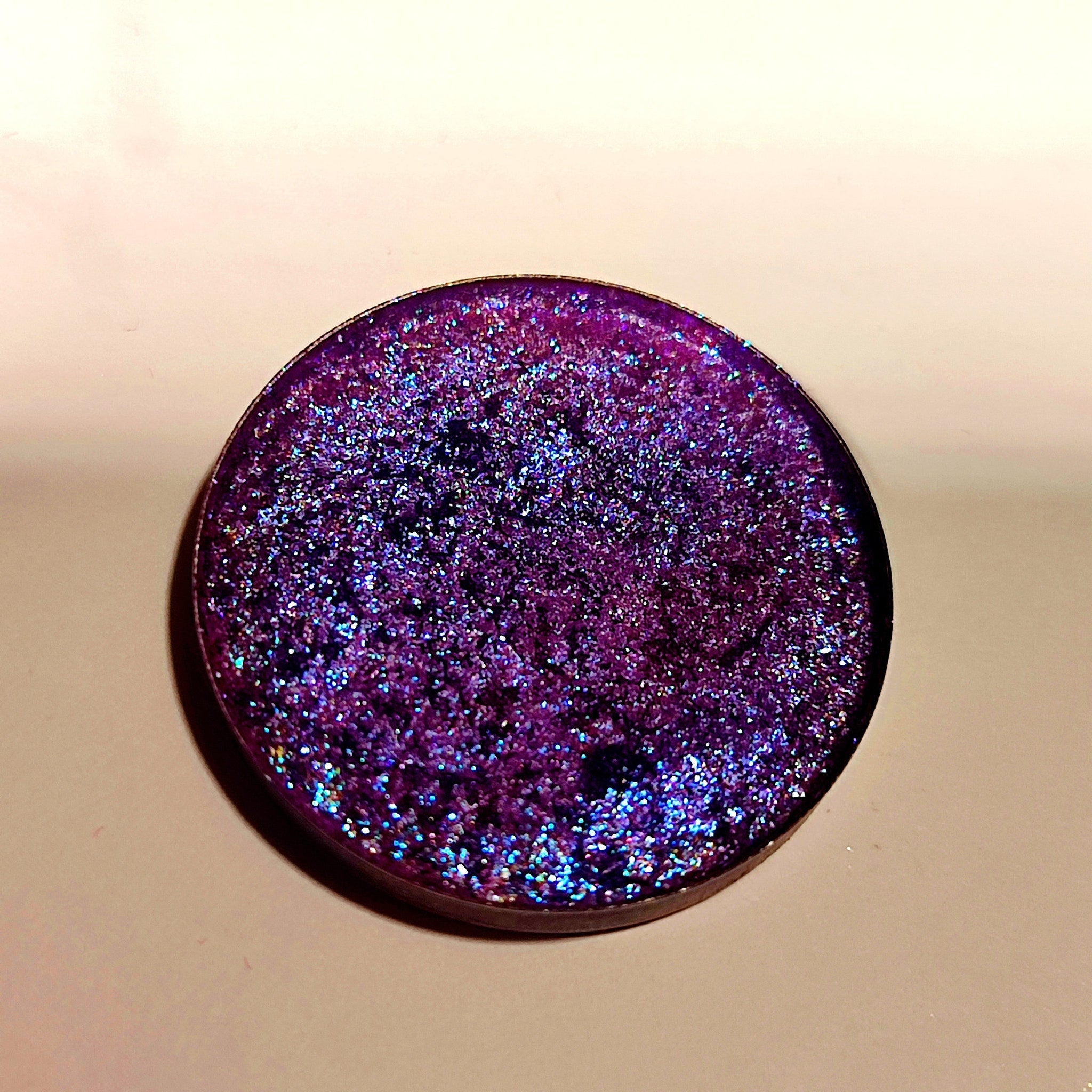 Purple eyeshadow with glitter, round compact, and metallic rim.