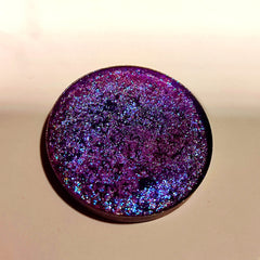 Purple eyeshadow with glitter, round compact, and metallic rim.