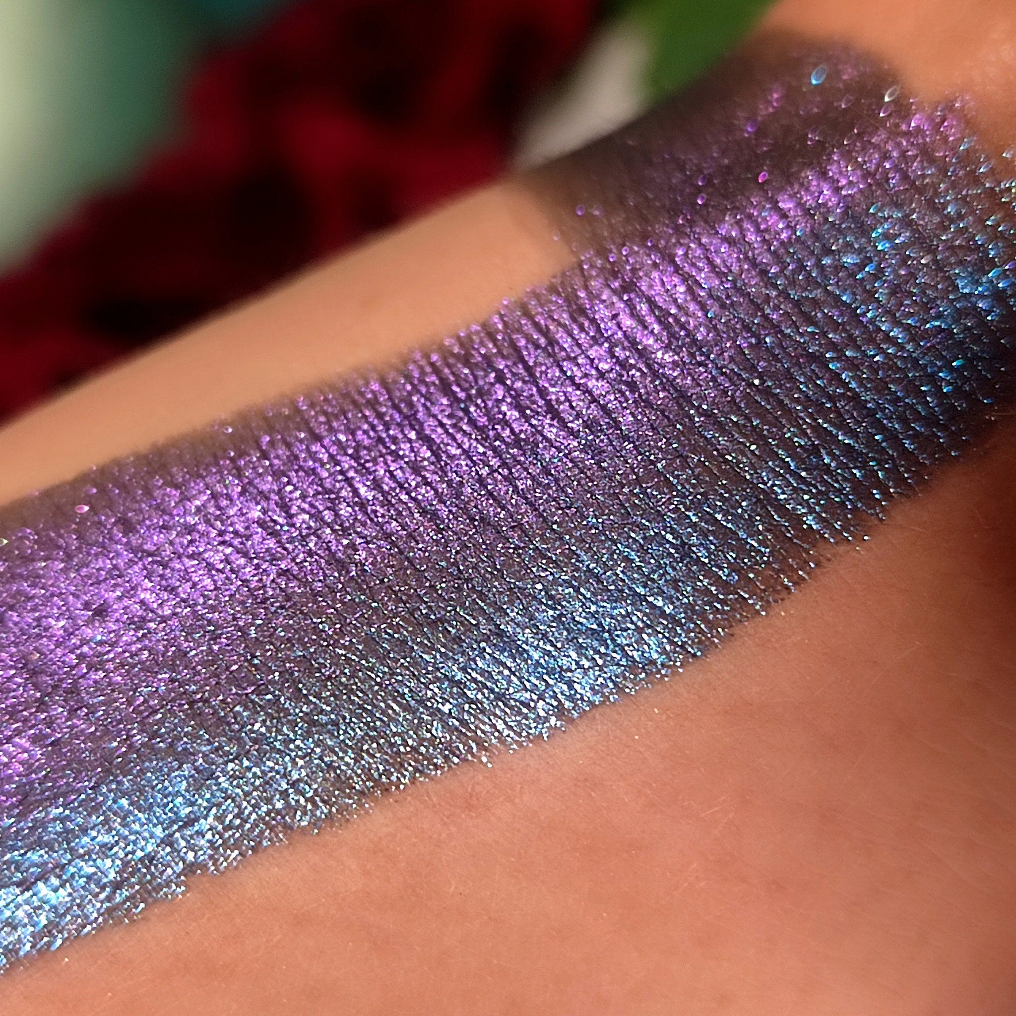 Eyeshadow swatch with iridescent purple and blue shimmer on skin, showing color and texture