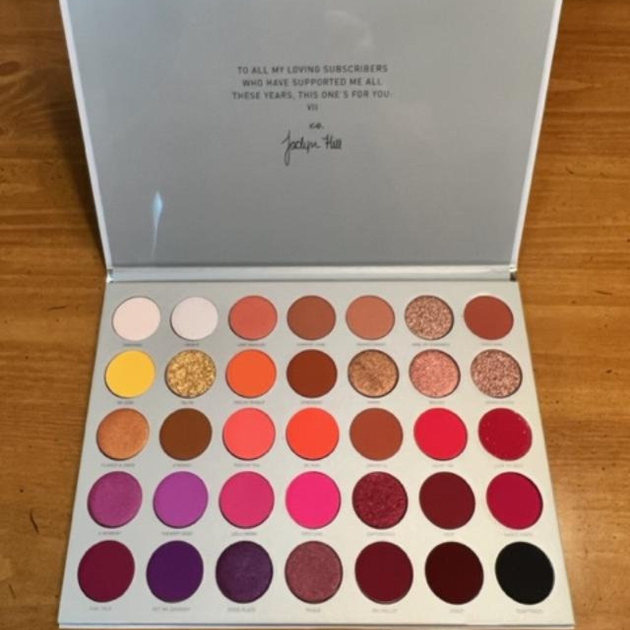 Eyeshadow palette with multiple colors, glitter, and Jaclyn Hill branding on lid