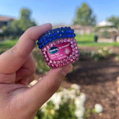 Lip balm with blue and pink rhinestones, Vaseline branding, held in hand
