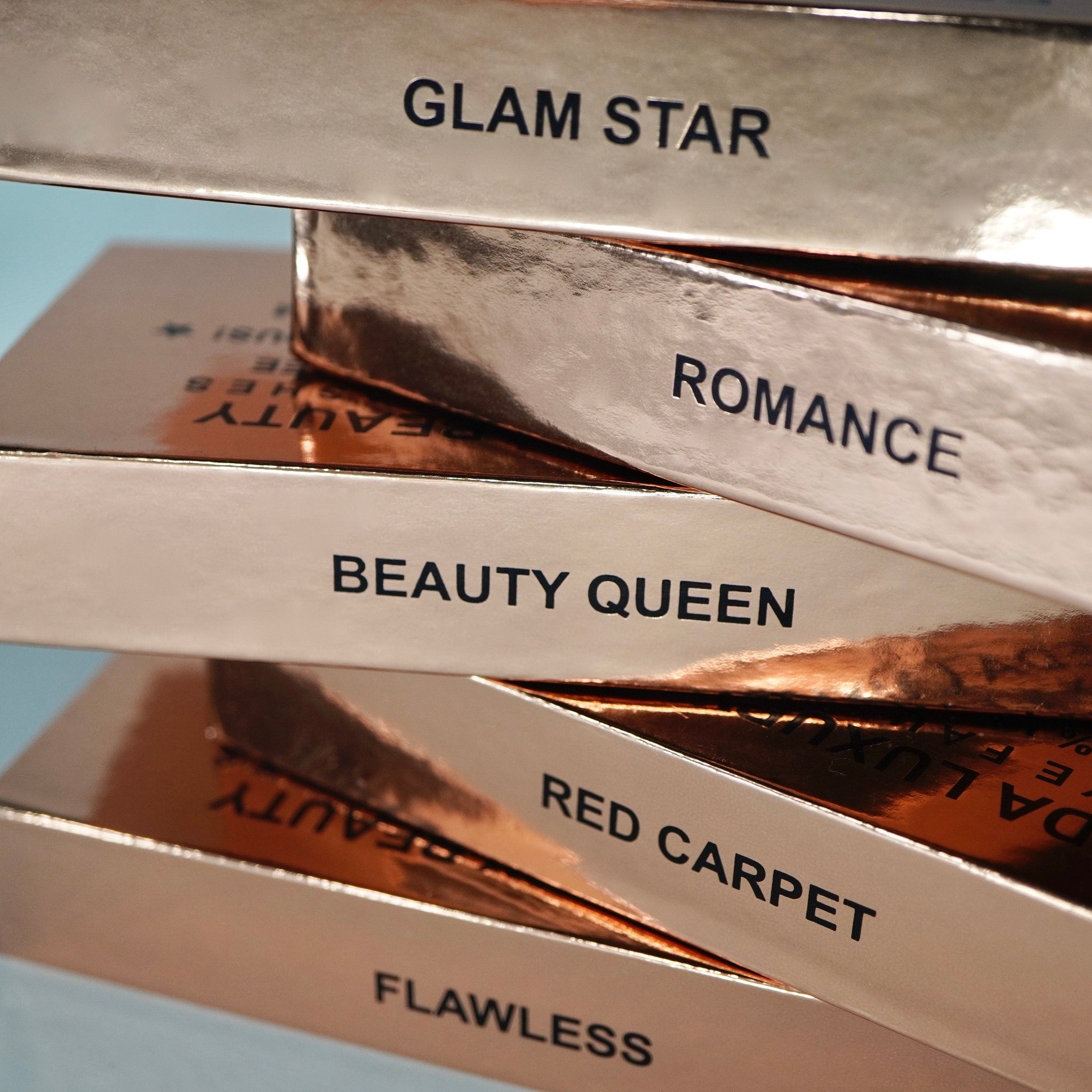Boxes with metallic rose gold finish, black text, stacked for display