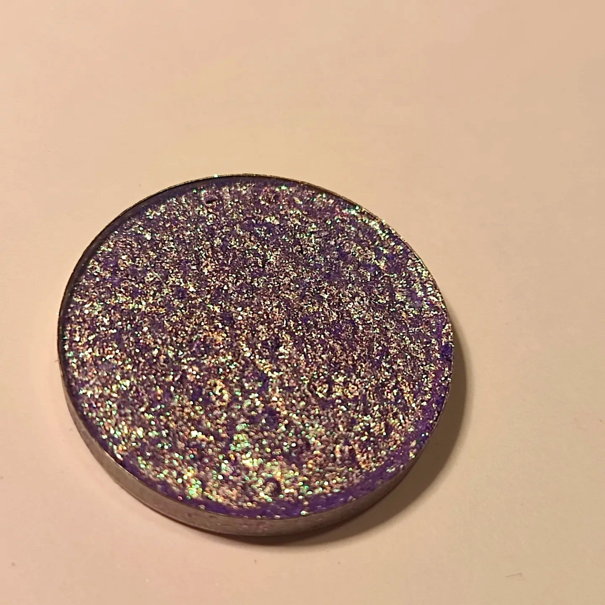 Close-up of a makeup brush applying vibrant blue-violet eye shadow to eyelid, showcasing rich pigment and smooth blendability