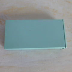 Box, teal rectangular shape, solid color, on a textured surface