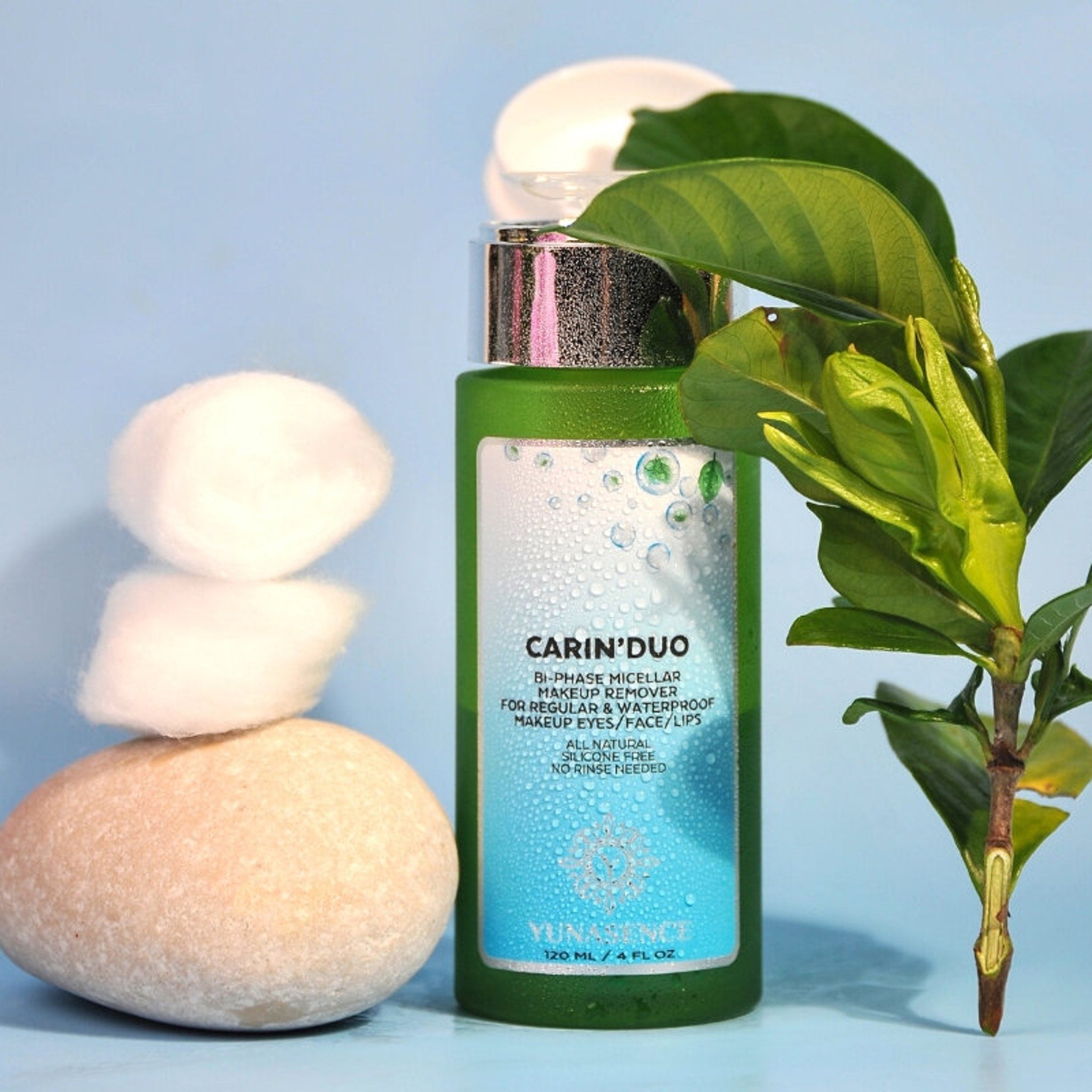 Makeup remover bottle, green glass, silver cap, with Yunasence label, cotton balls, and green leaves